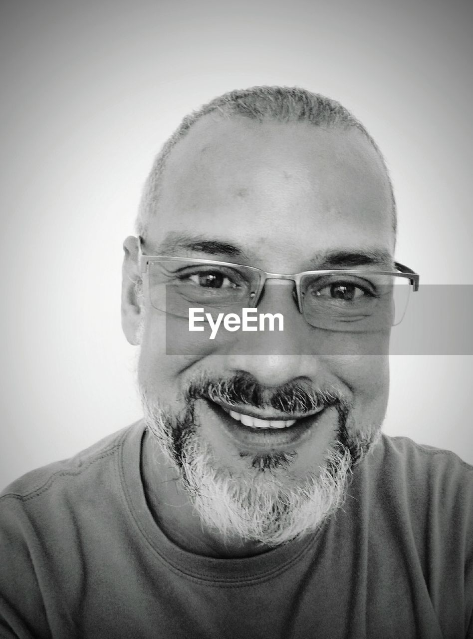 Close-up portrait of smiling man against wall