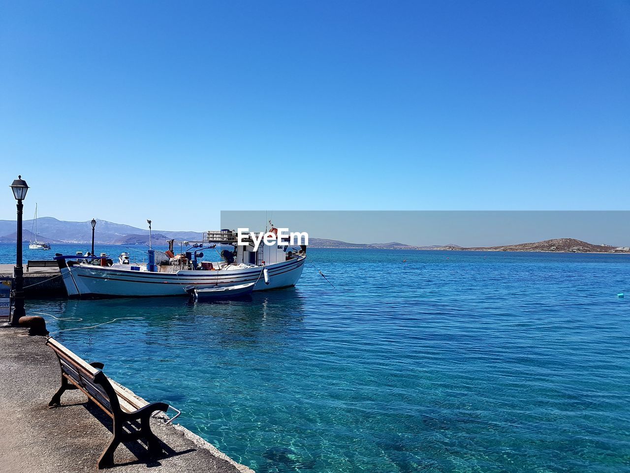 Boats moored on sea against clear blue sky