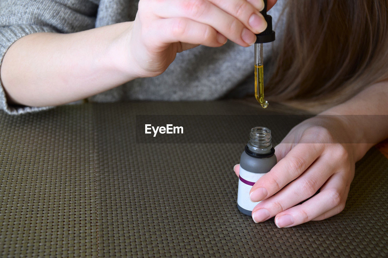 Bottle of cosmetic oil with dropper in hands of young girl. woman's hands with essential oil.