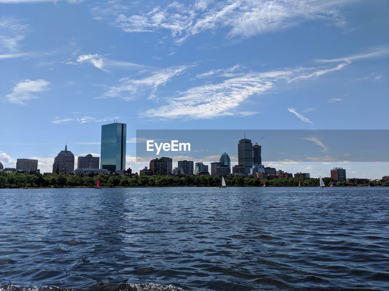 SEA BY MODERN BUILDINGS AGAINST SKY