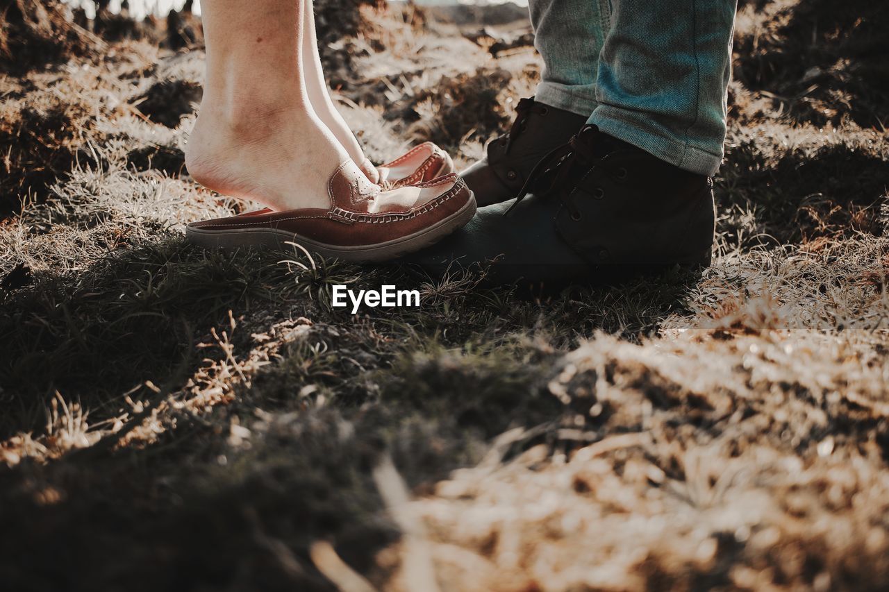 Low section of couple standing on field