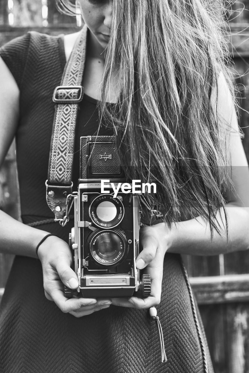 CLOSE-UP OF YOUNG WOMAN PHOTOGRAPHING CAMERA