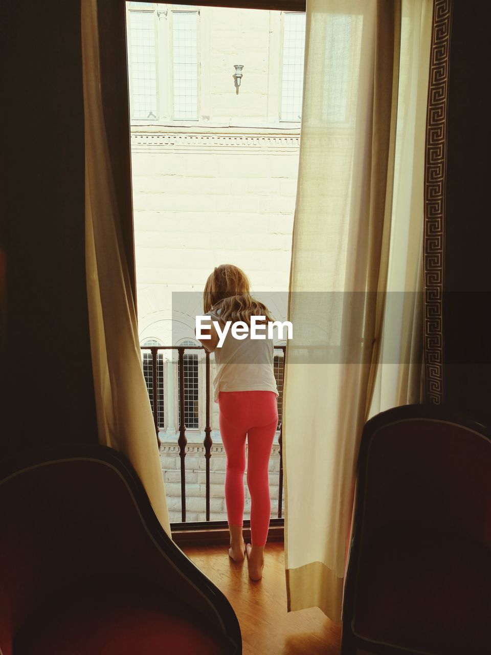 Rear view of girl leaning on railing at home