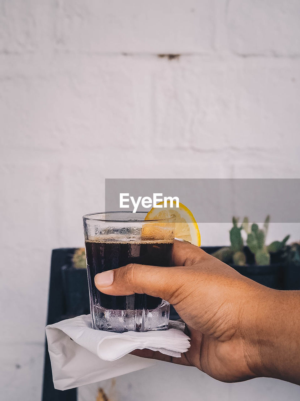 Midsection of person holding drink against glass wall