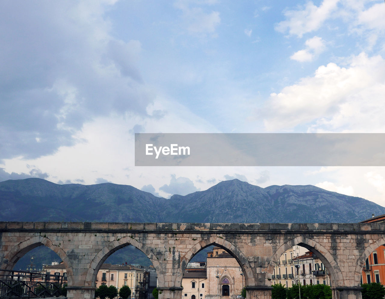 Arch bridge over mountain against cloudy sky