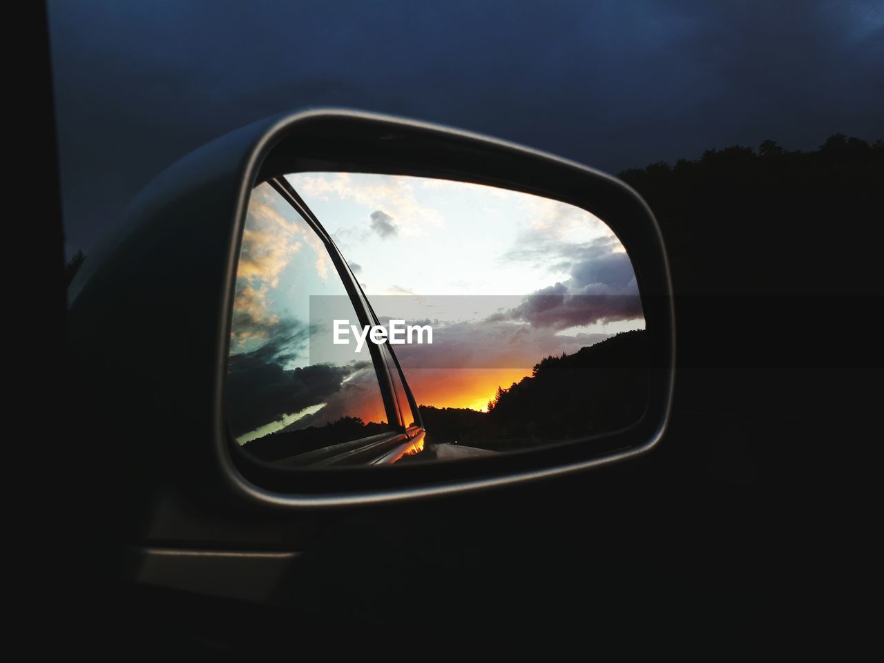 REFLECTION OF SKY ON SIDE-VIEW MIRROR OF CAR ON ROAD