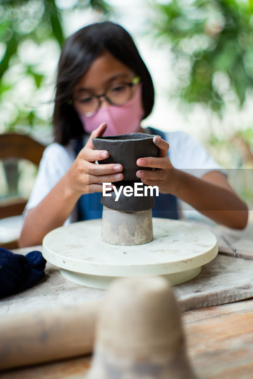 Girl making pot on pottery wheel