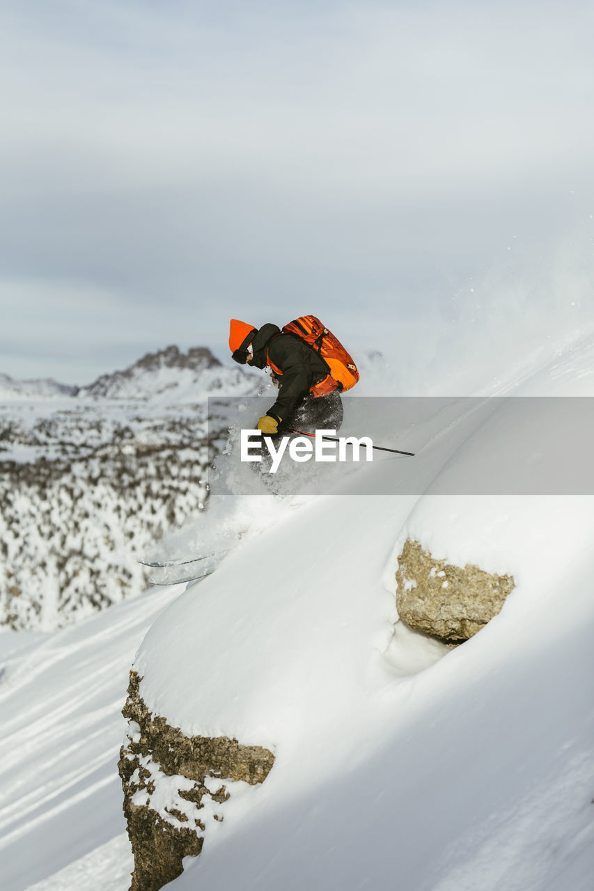 Side view of hiker with backpack skiing on snowcapped mountain