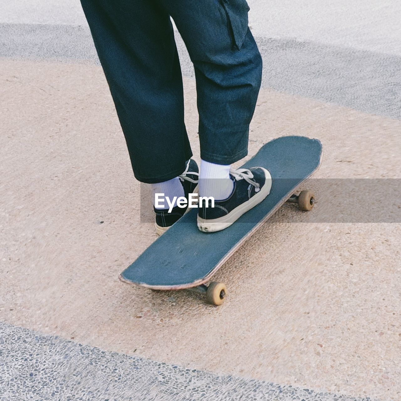 LOW SECTION OF PERSON WITH SKATEBOARD STANDING ON FLOOR