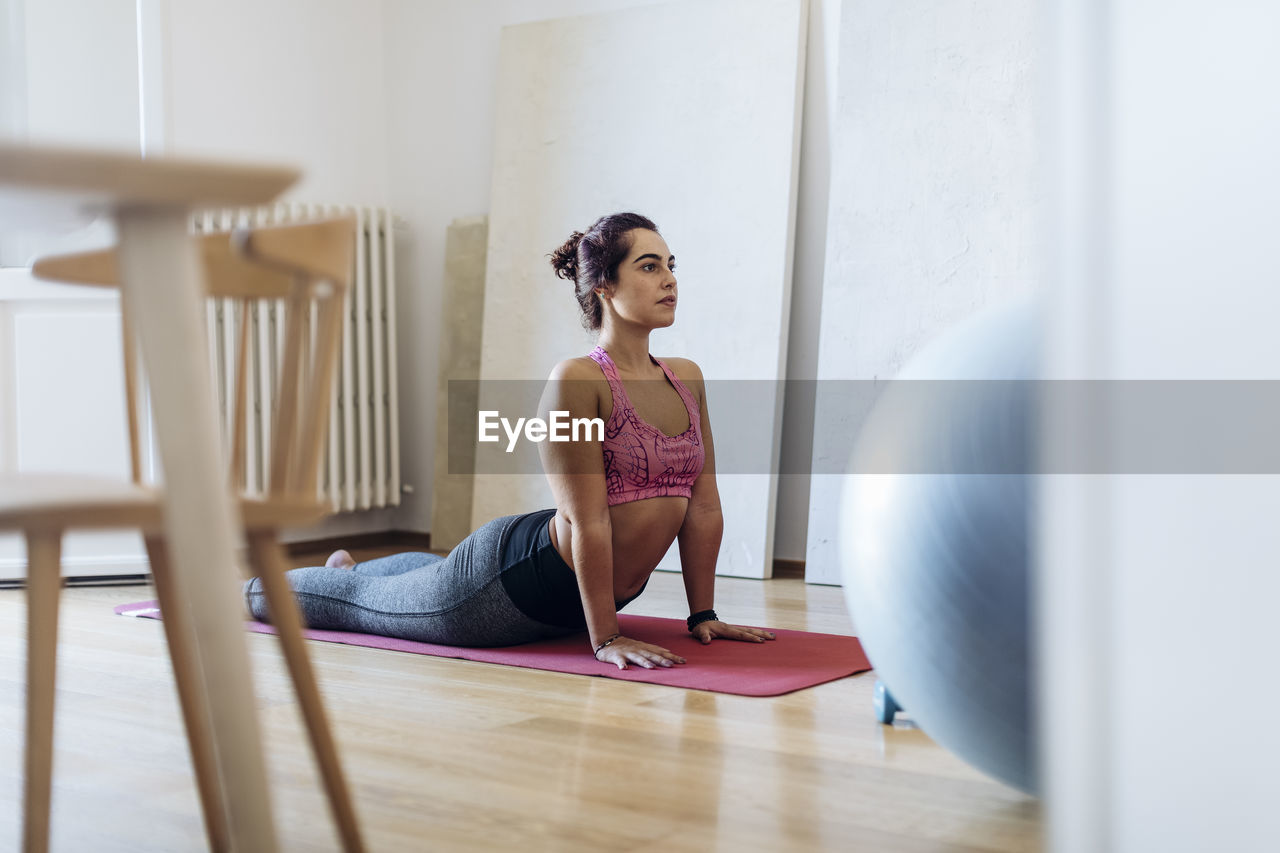 Focused ethnic woman practicing yoga at home
