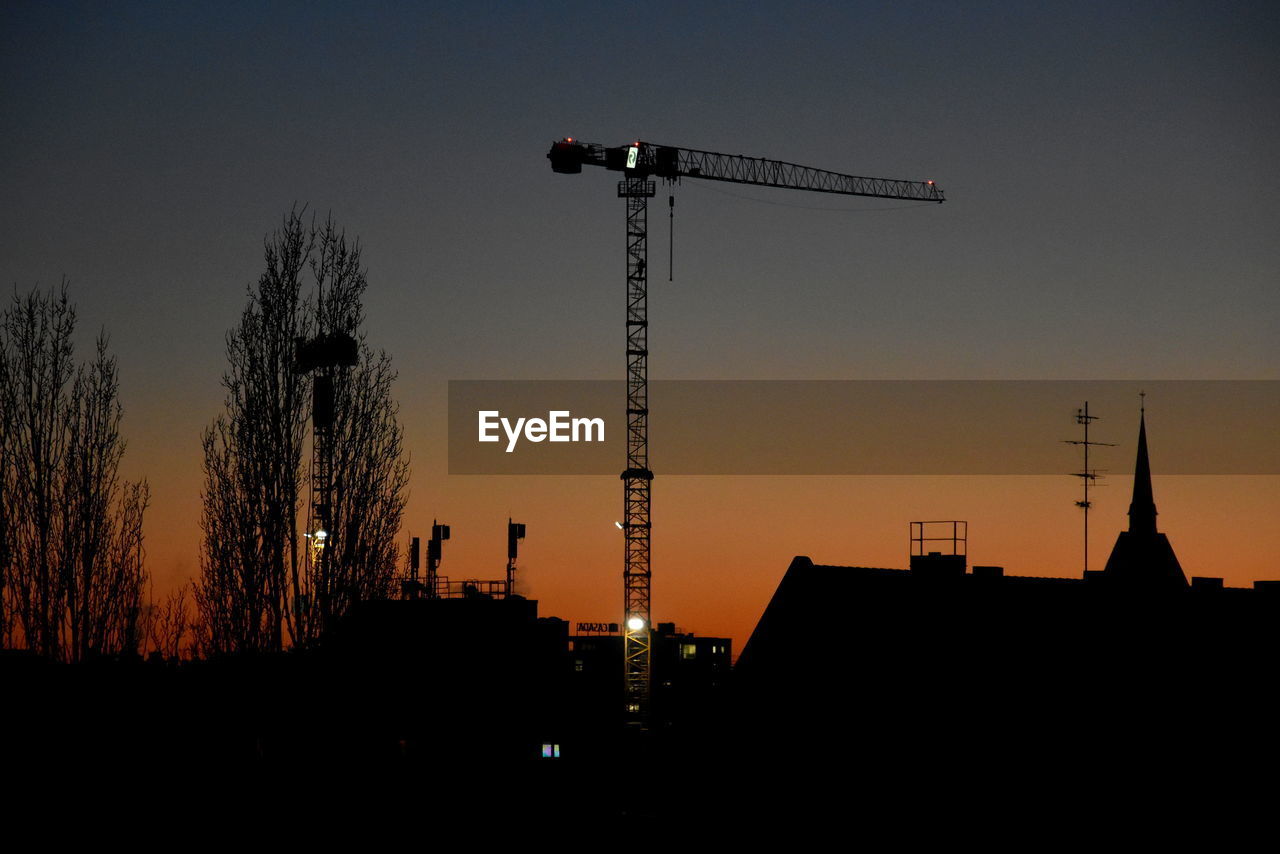 sky, silhouette, architecture, built structure, crane - construction machinery, dusk, evening, sunset, building exterior, machinery, nature, industry, night, construction industry, no people, tree, construction site, city, building, development, outdoors, light, horizon, street light, clear sky, skyline, tower, cloud