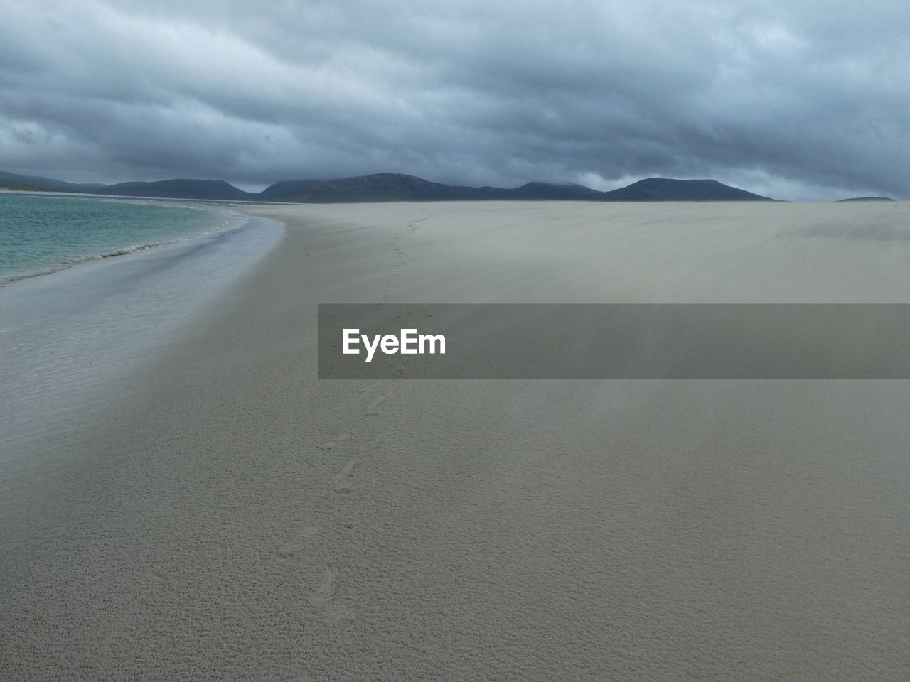 SCENIC VIEW OF SAND DUNE ON BEACH AGAINST SKY