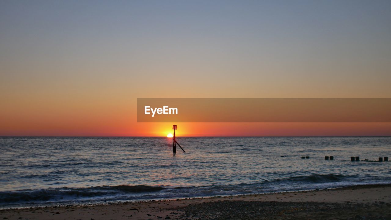 sea, sky, water, sunset, beach, horizon, horizon over water, land, beauty in nature, scenics - nature, ocean, orange color, nature, shore, wave, tranquility, body of water, tranquil scene, sun, silhouette, idyllic, wind wave, dawn, coast, clear sky, one person, motion, holiday, vacation, sports, sunlight, trip, sand, copy space, travel destinations, leisure activity, outdoors, afterglow, evening, lifestyles, travel, seascape, non-urban scene, urban skyline, environment, summer, standing, full length