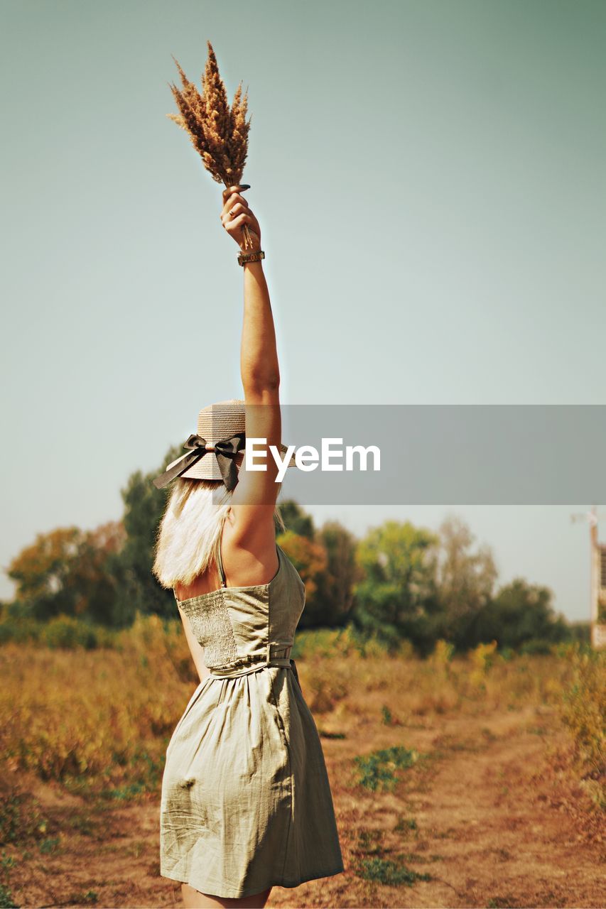 Midsection of woman standing on field against clear sky