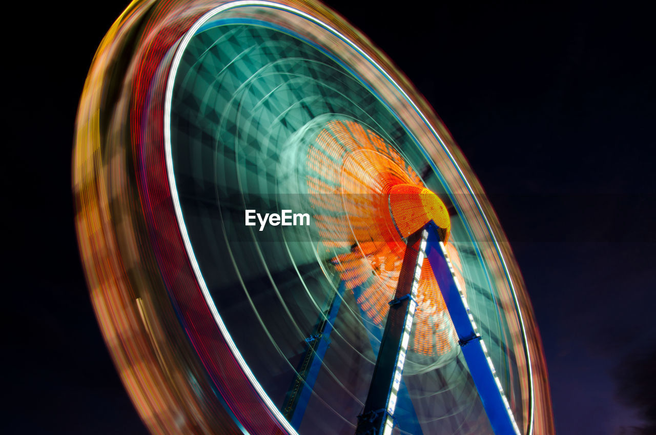 Blurred motion of ferris wheel against sky at night