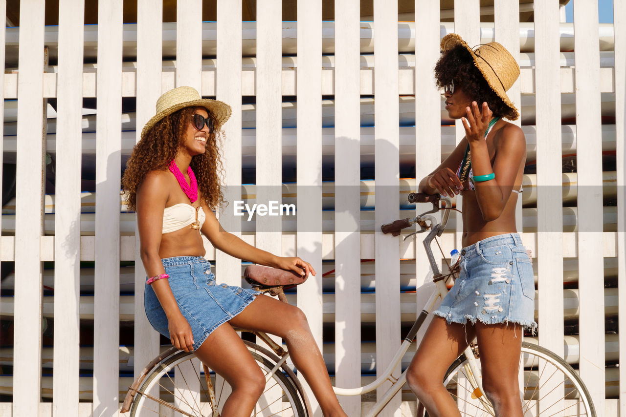 Two young black women having conversation at the beach smiling