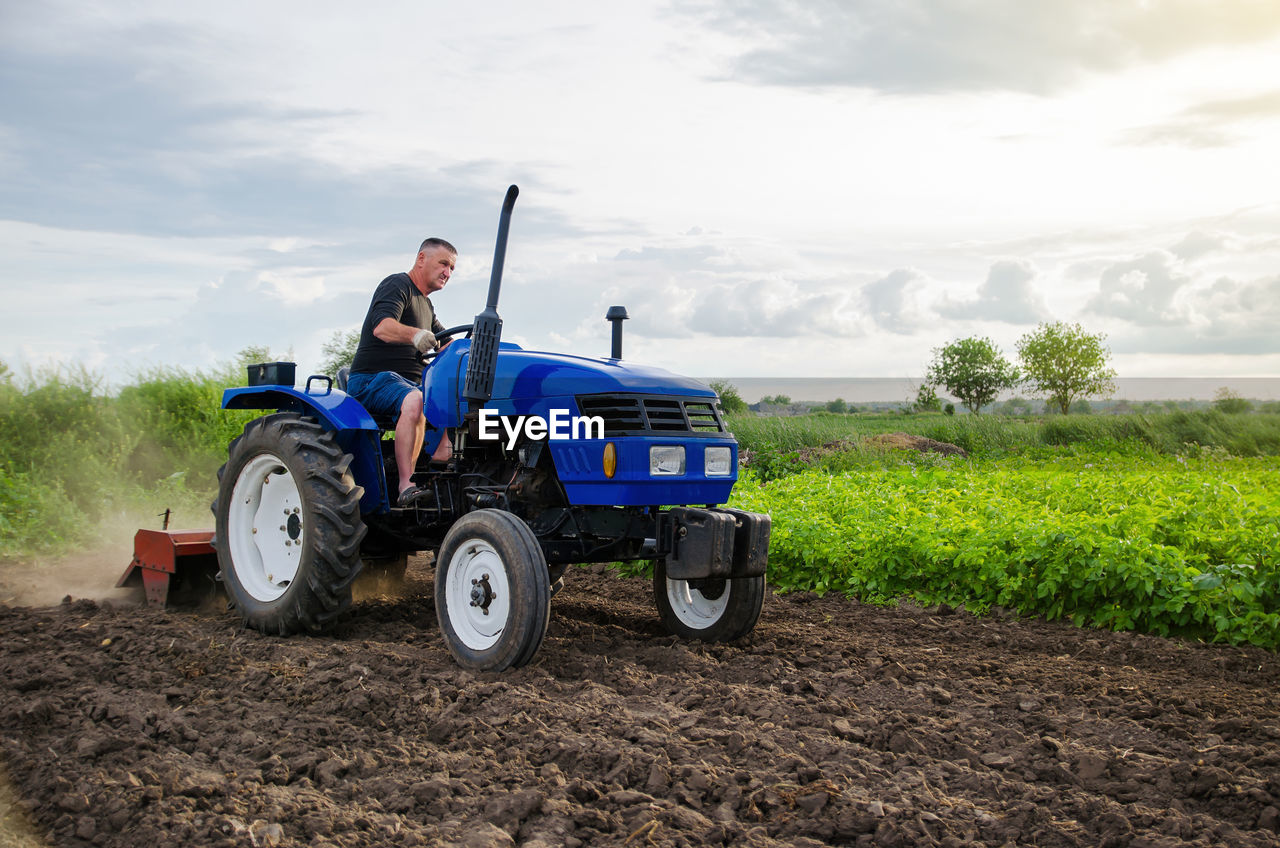 Farmer on tractor cultivates farm field. milling soil, crushing and loosening ground