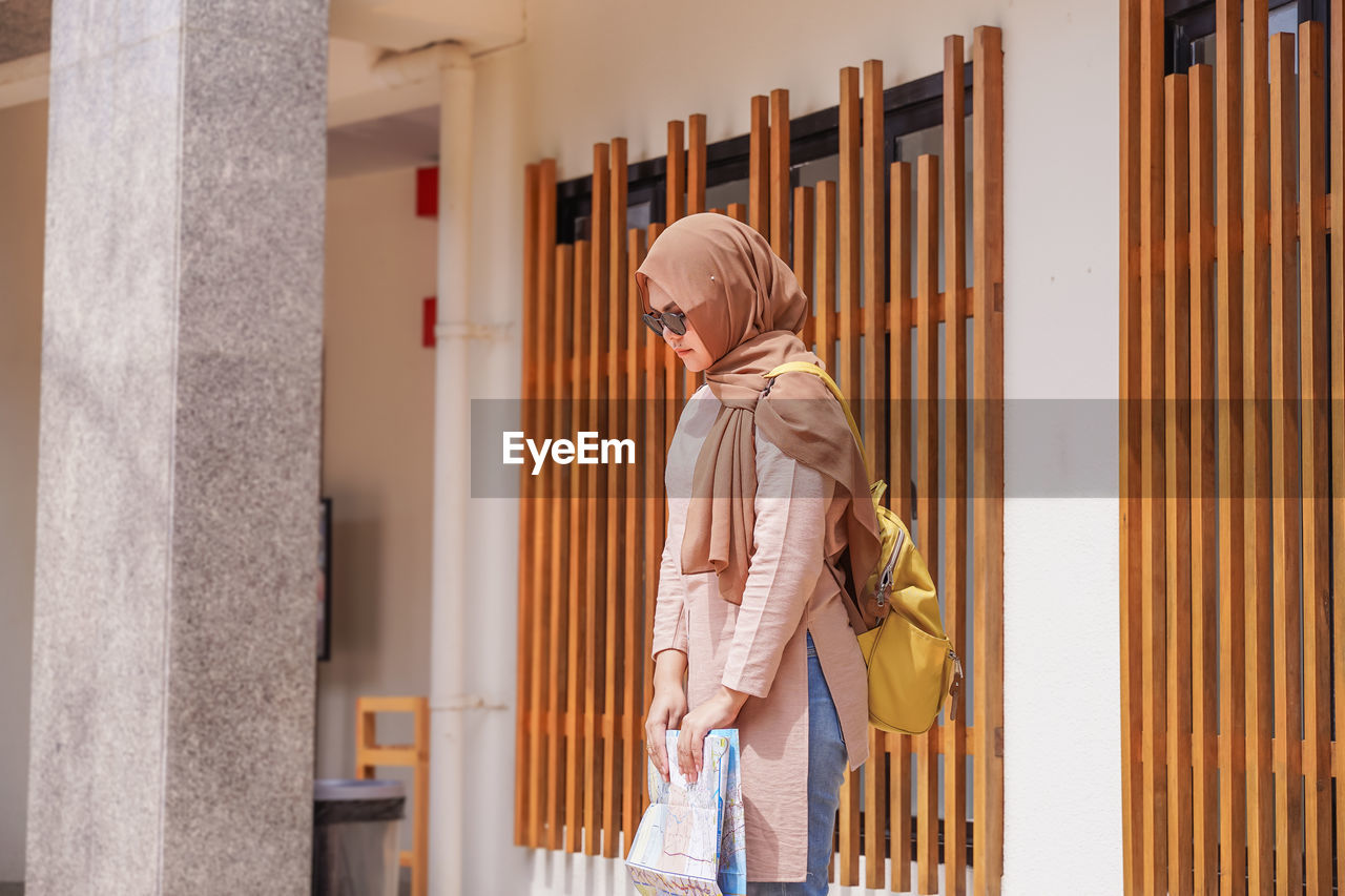 Woman wearing hijab standing against building