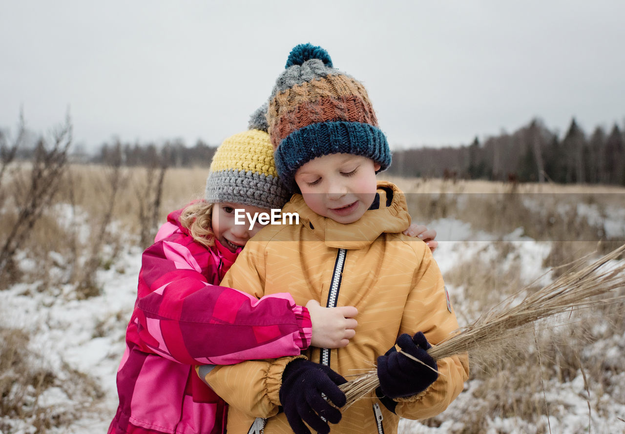 Siblings cuddling whilst playing outside in the snow