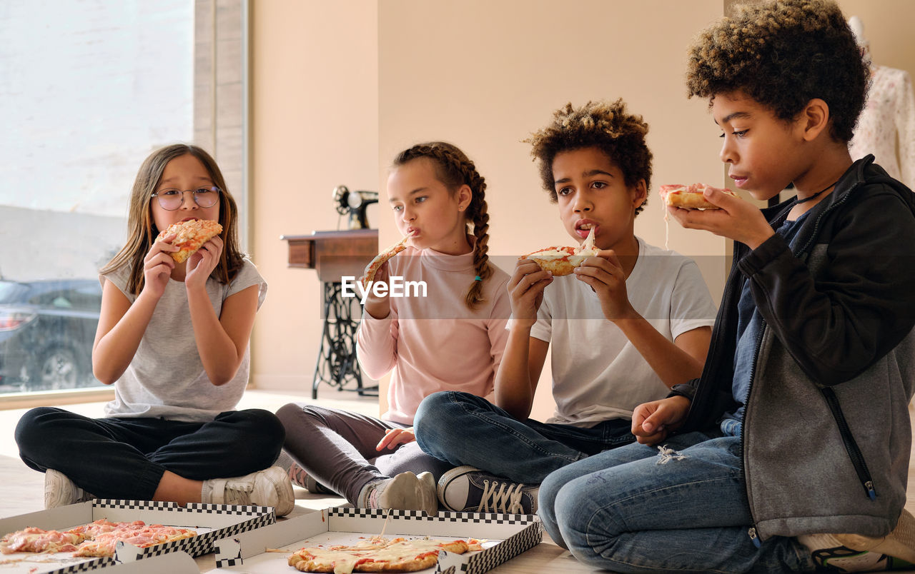 GROUP OF PEOPLE EATING FOOD IN KITCHEN