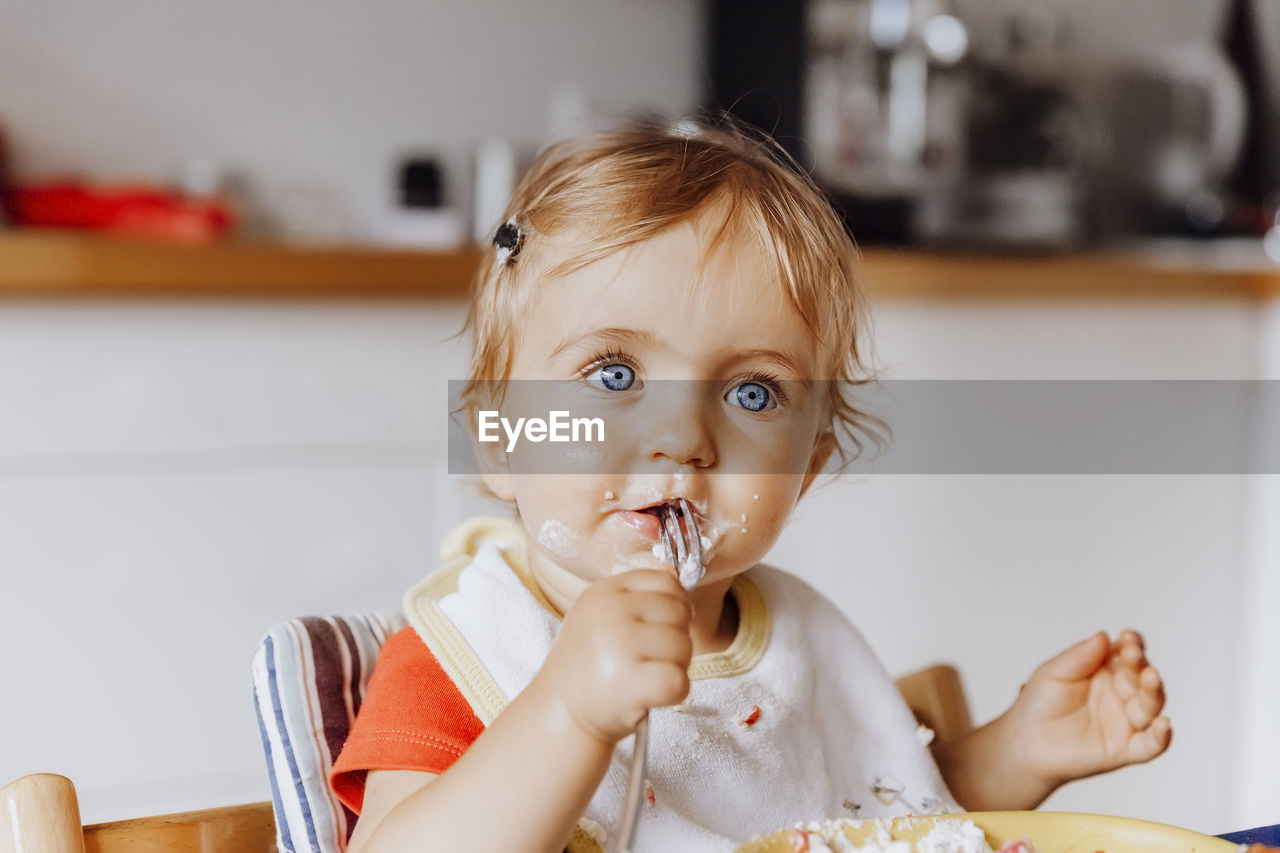 Portrait of cute girl eating food while sitting at home