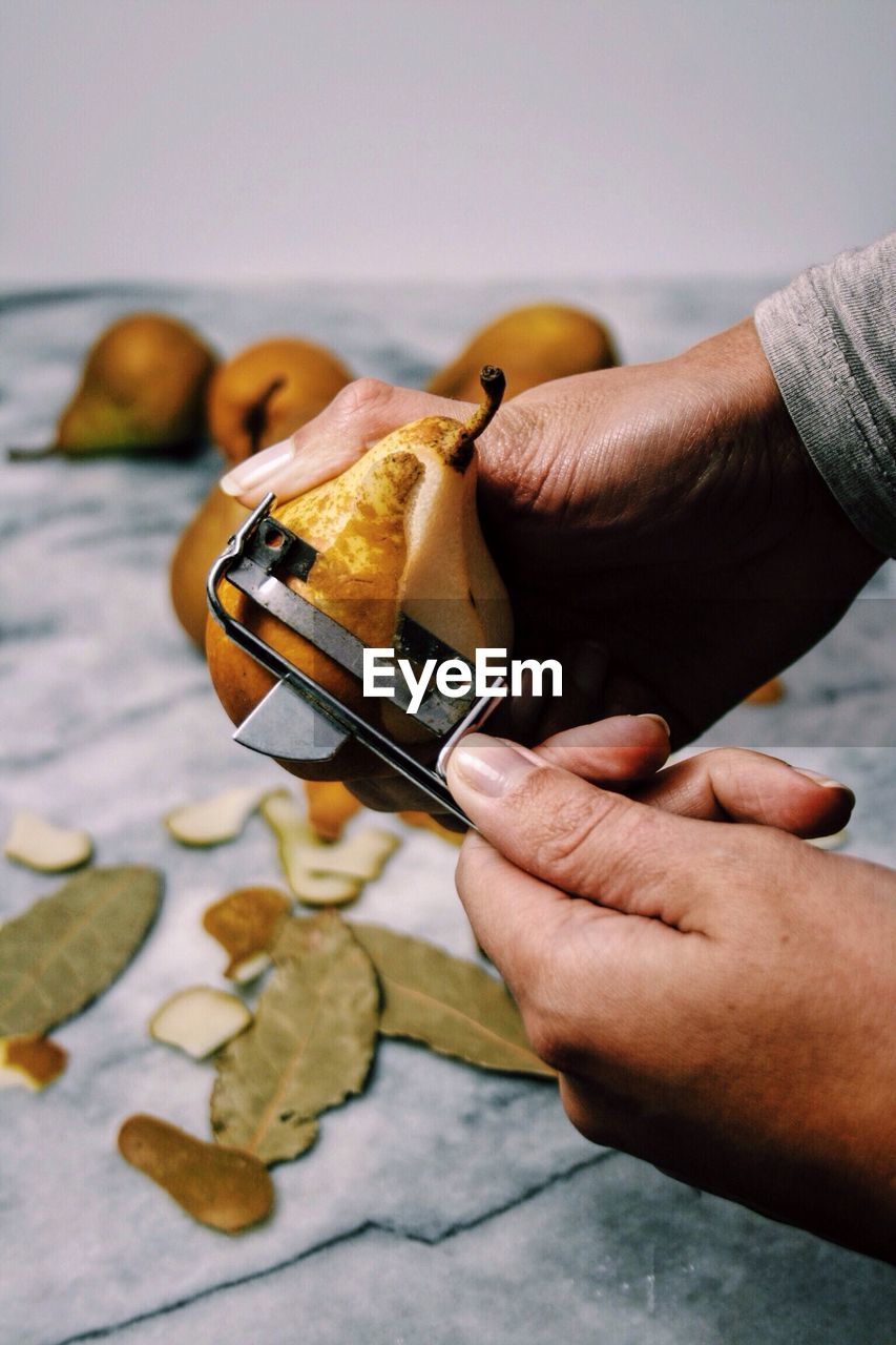 Cropped image of person peeling pear on table
