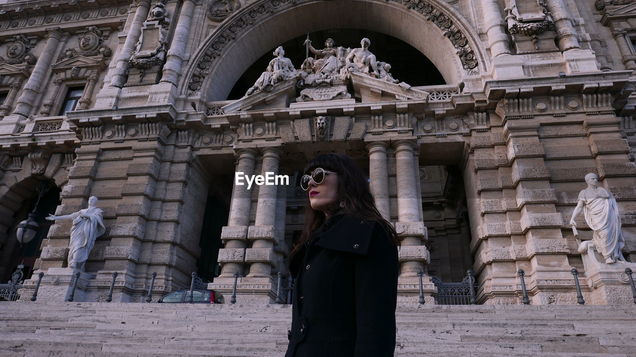 WOMAN STANDING AGAINST BUILDING