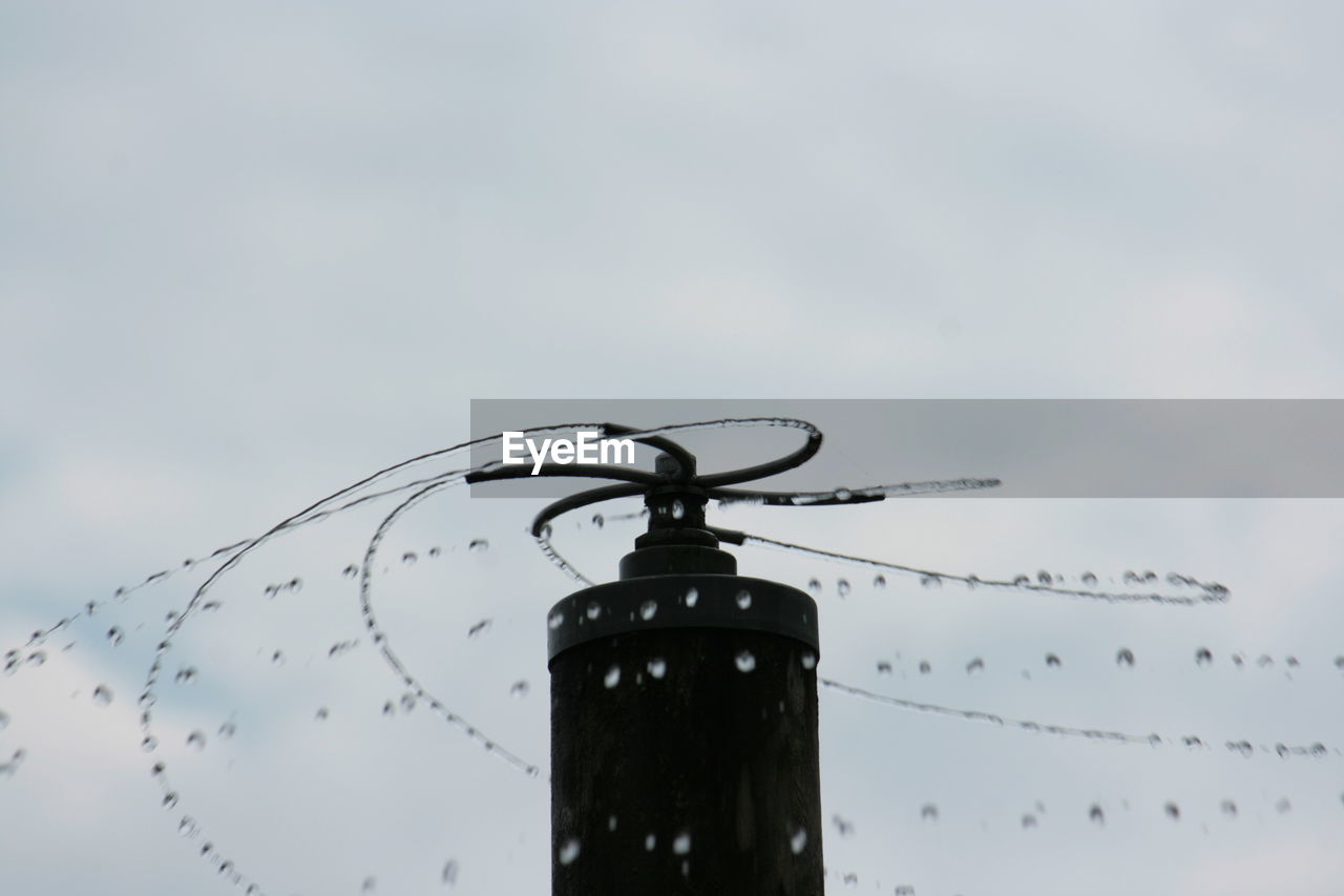 Low angle view of water sprinkler against sky