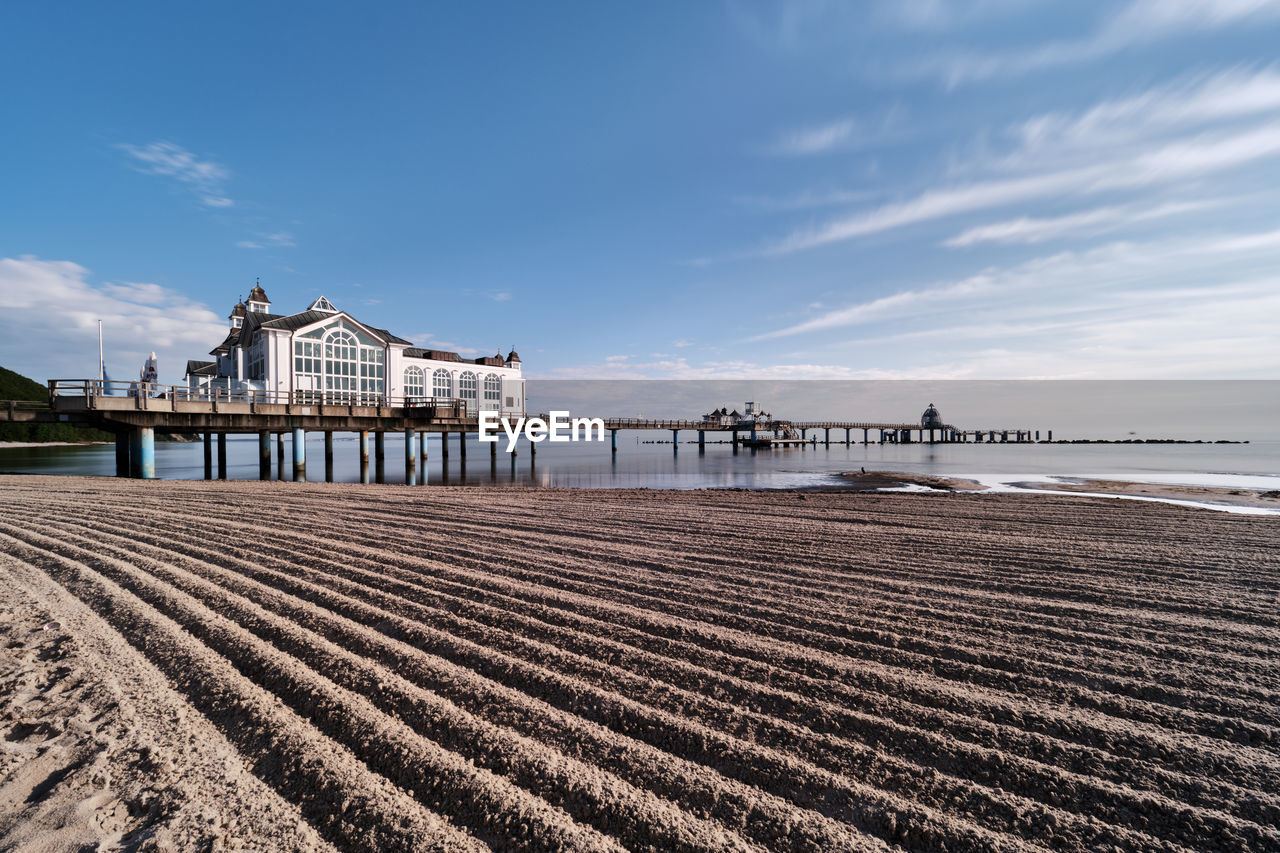 View of pier on beach against cloudy sky