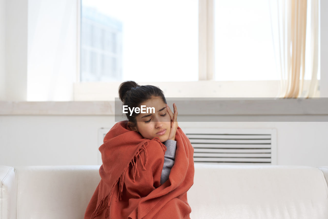 Portrait of young woman looking through window