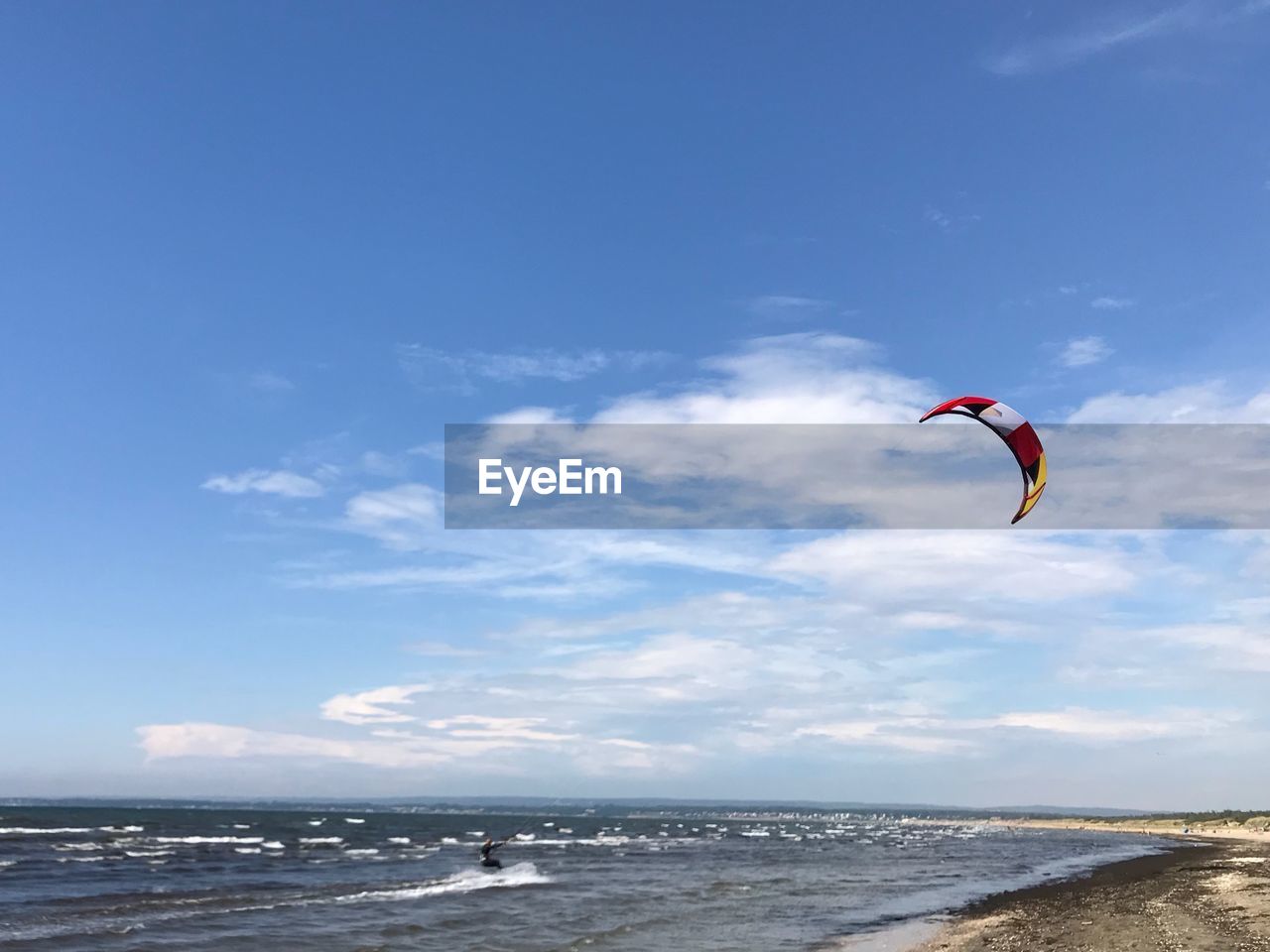 WOMAN FLYING OVER BEACH AGAINST SKY