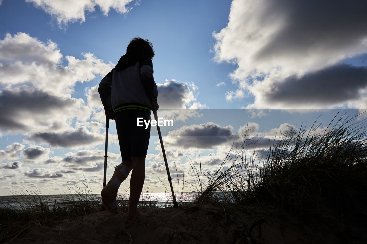 REAR VIEW OF SILHOUETTE PERSON STANDING ON BEACH