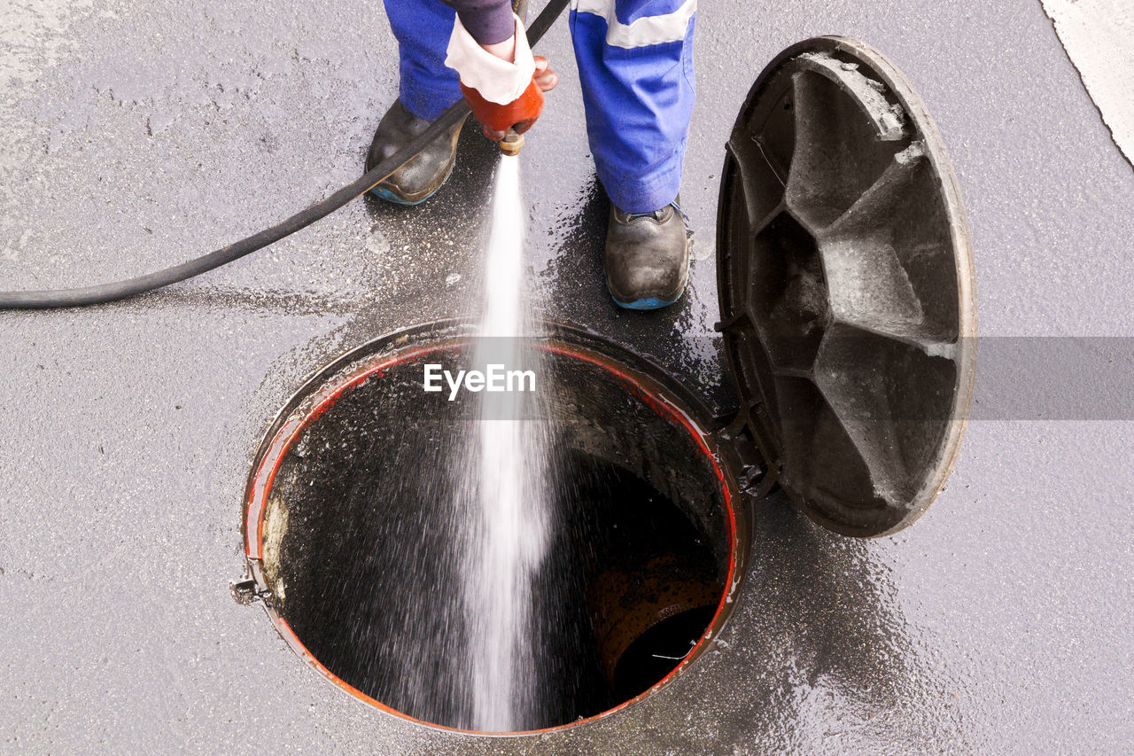 Low section of man cleaning manhole