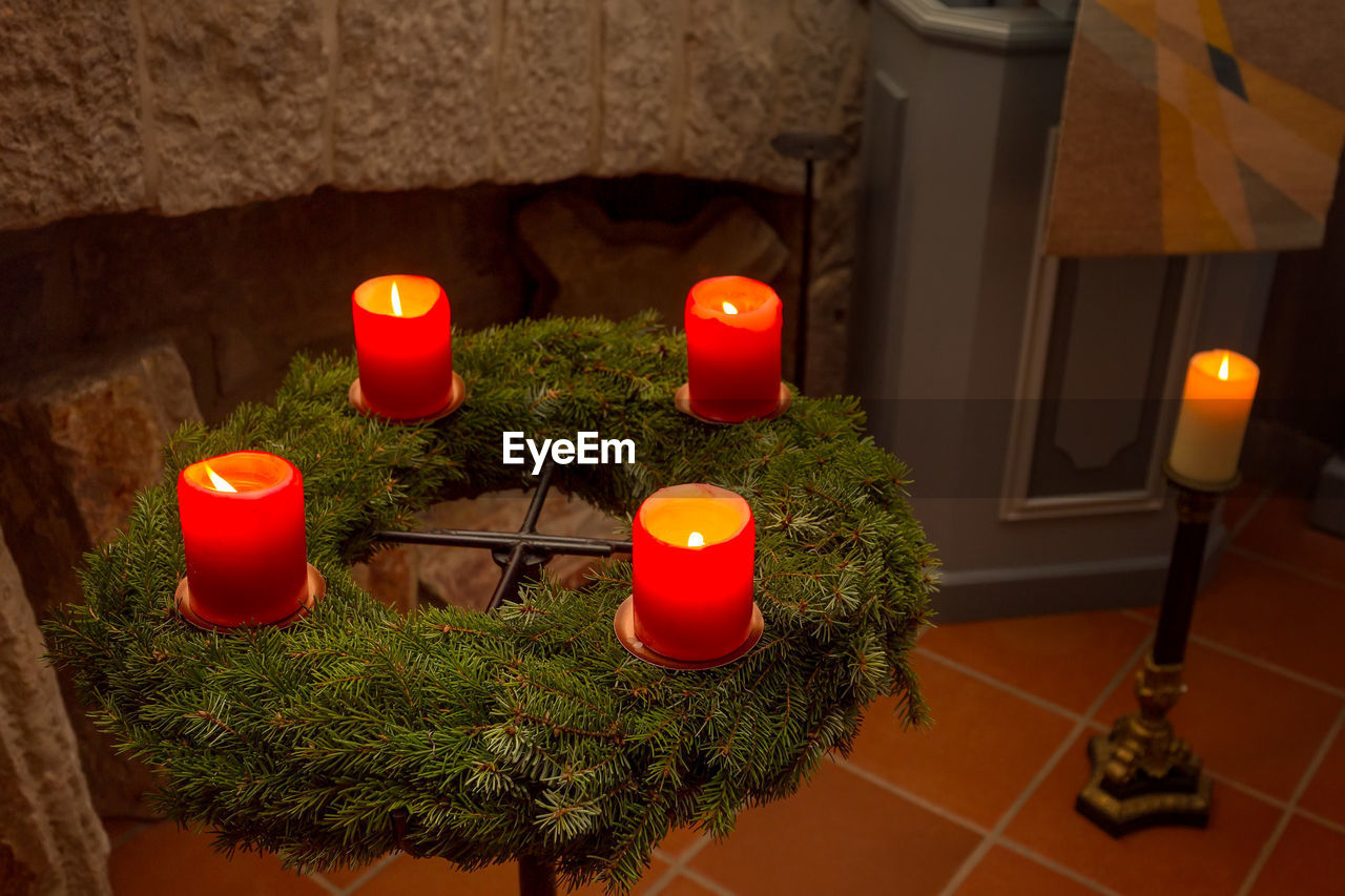 HIGH ANGLE VIEW OF ILLUMINATED TEA LIGHT CANDLES ON TABLE