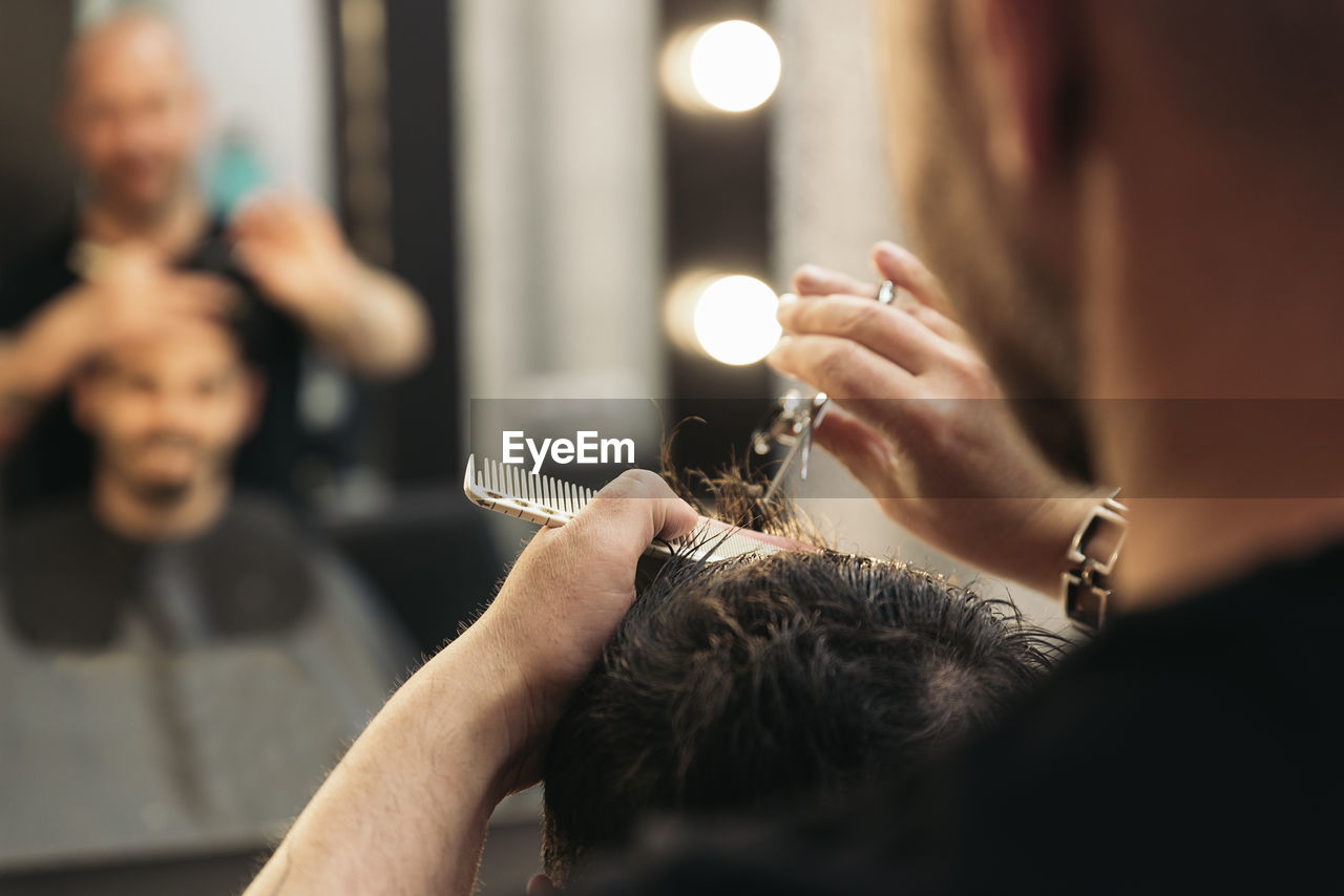 Midsection of barber cutting man hair in salon