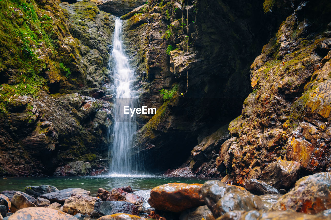 SCENIC VIEW OF WATERFALL ON ROCKS