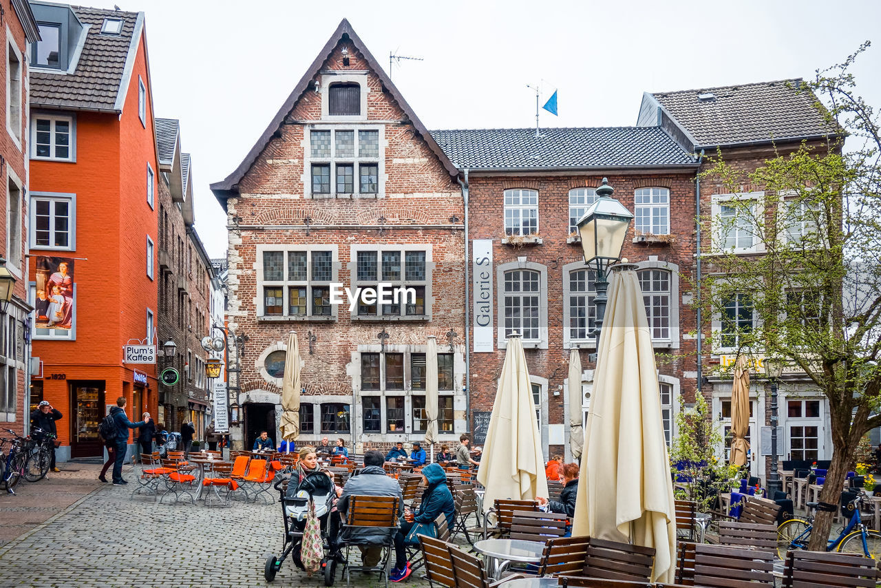 People sitting at outdoor restaurant against buildings