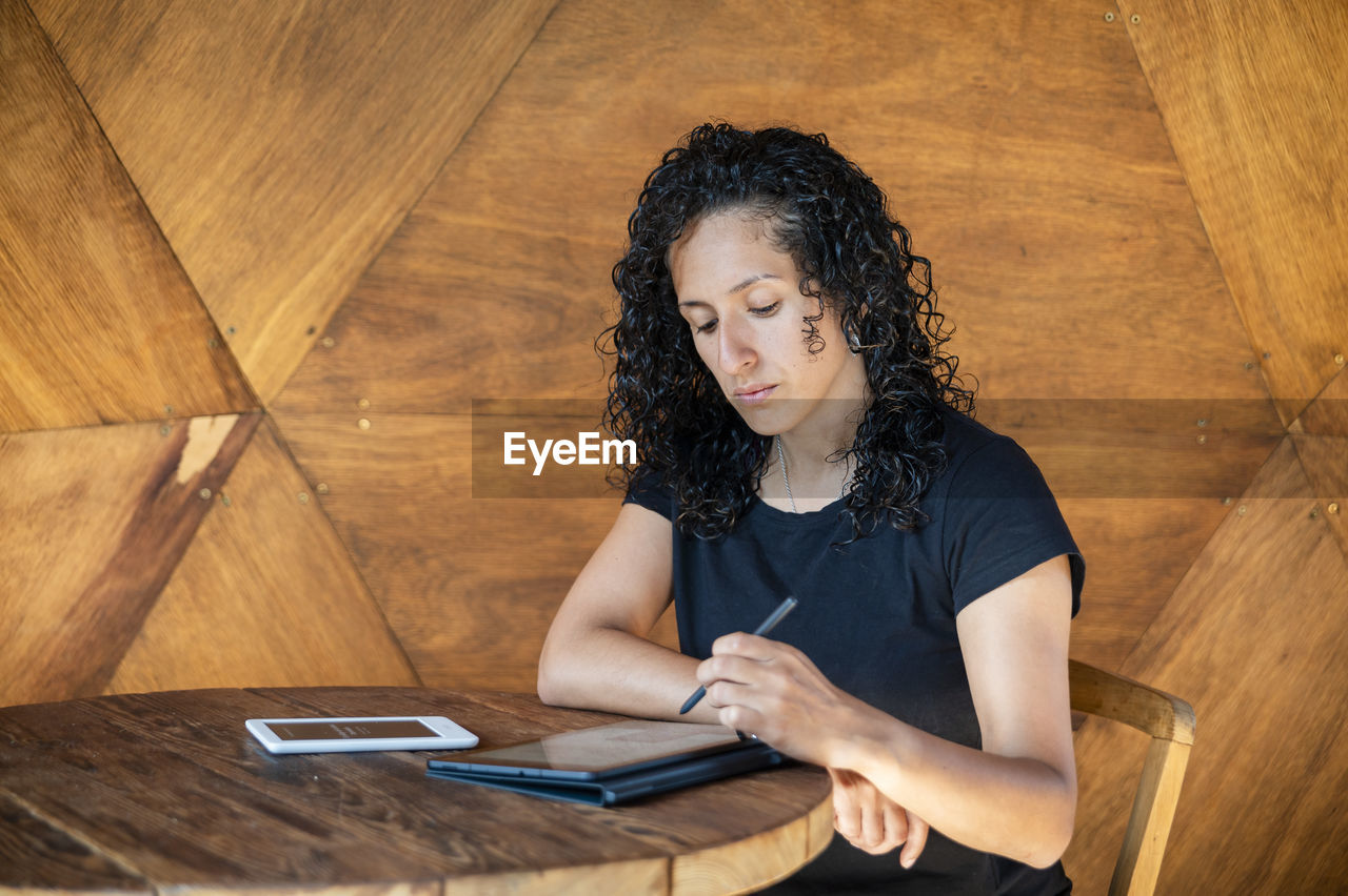 Woman using a digital tablet while sitting at a table.