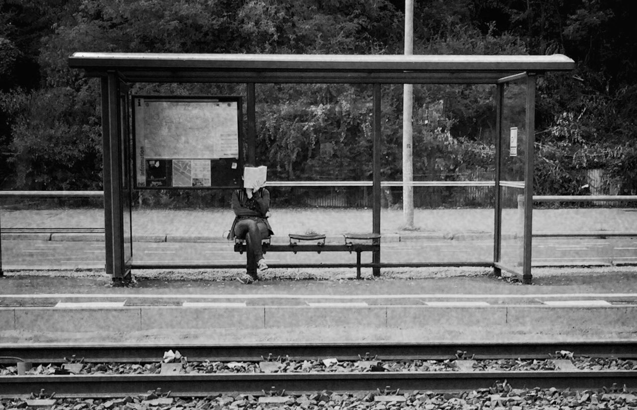 Woman reading book while sitting at railroad station