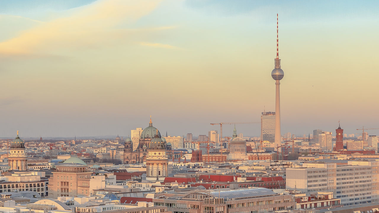 Fernsehturm amidst cityscape against sky during sunset