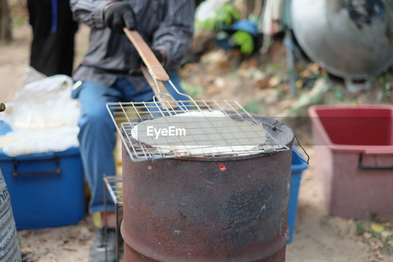 Low section of man preparing food on barbecue grill