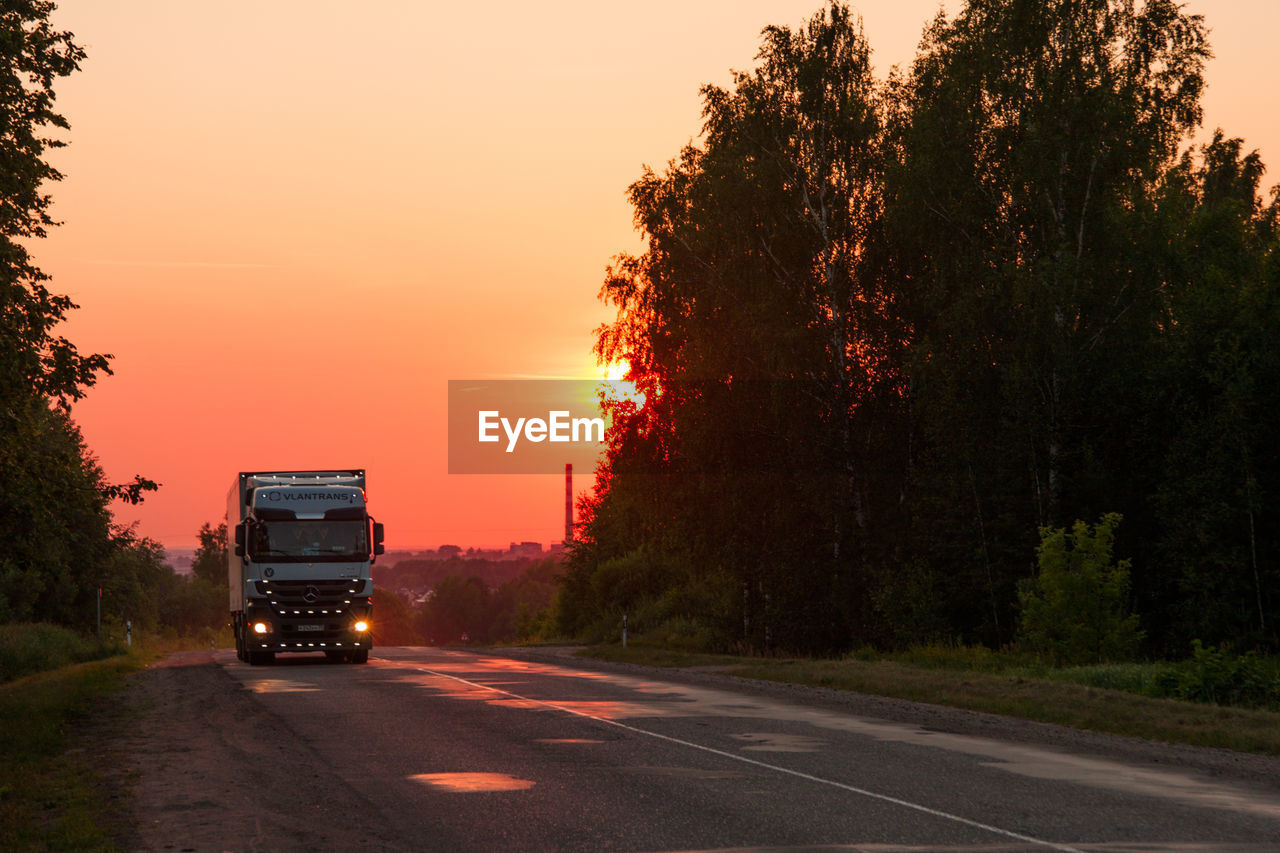 Cars on road against sky during sunset