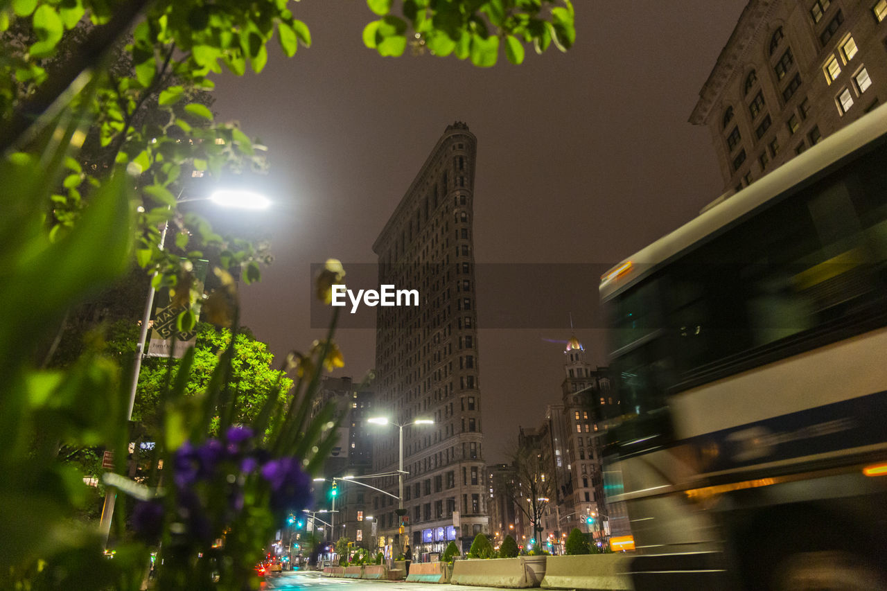 LOW ANGLE VIEW OF ILLUMINATED CITY BUILDINGS AT NIGHT