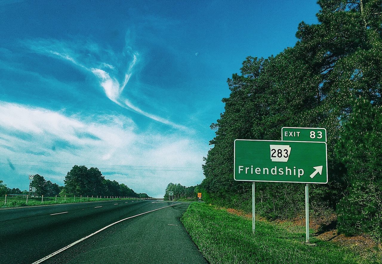 Road by information sign against sky