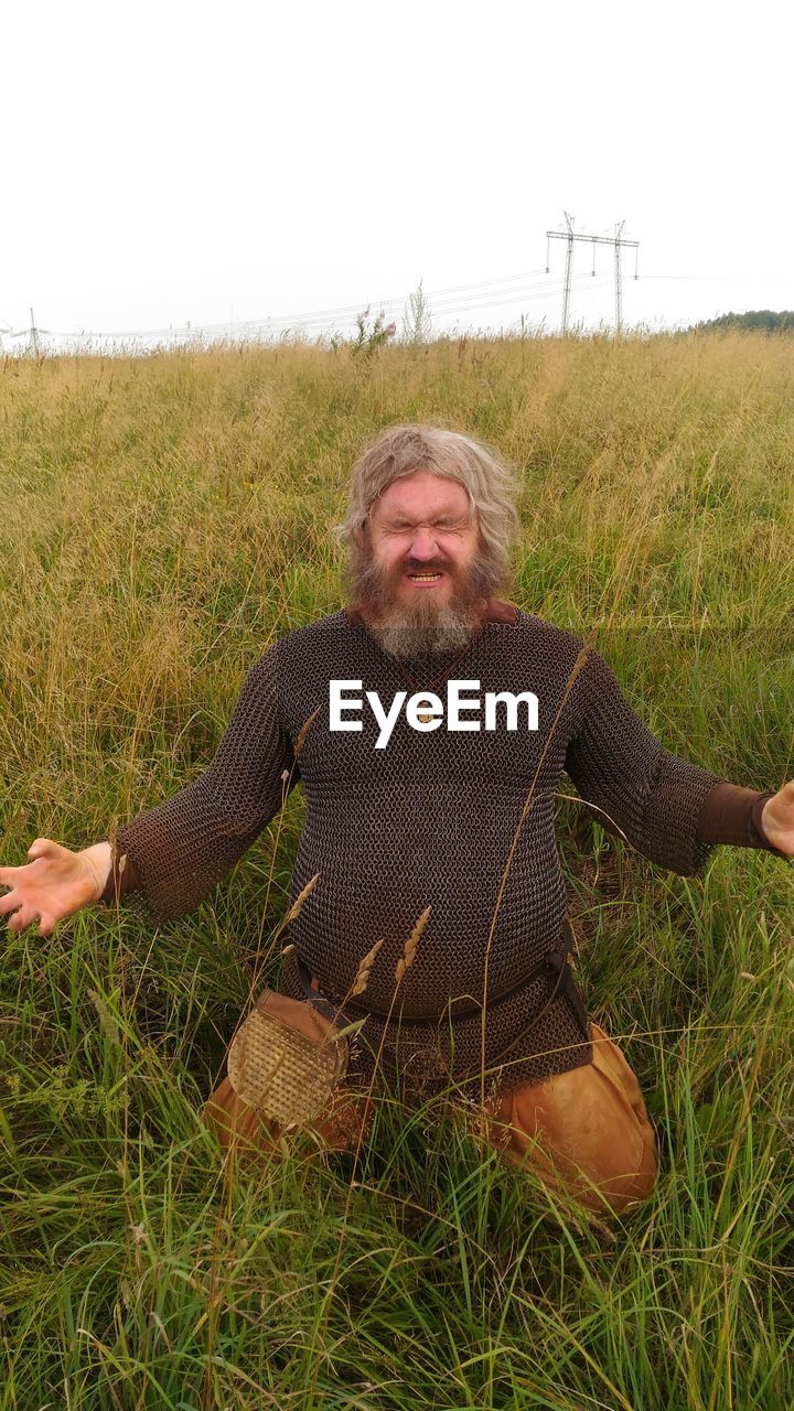 PORTRAIT OF MAN ON GRASS FIELD