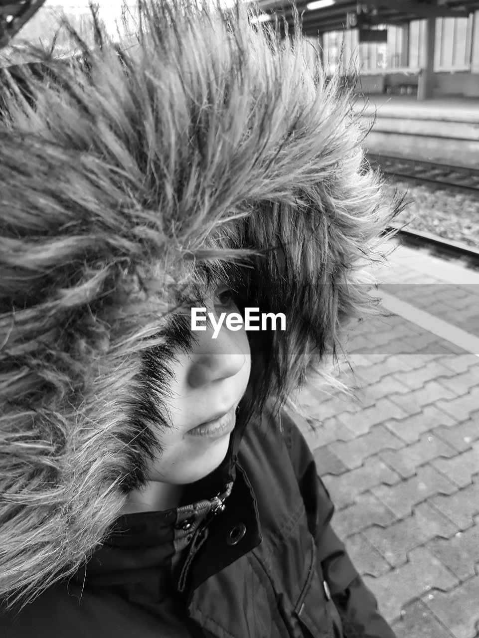 Close-up of boy wearing fur coat at railroad station platform