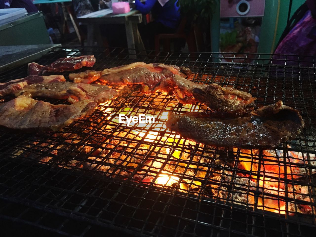 CLOSE-UP OF MEAT ON BARBECUE GRILL AT NIGHT