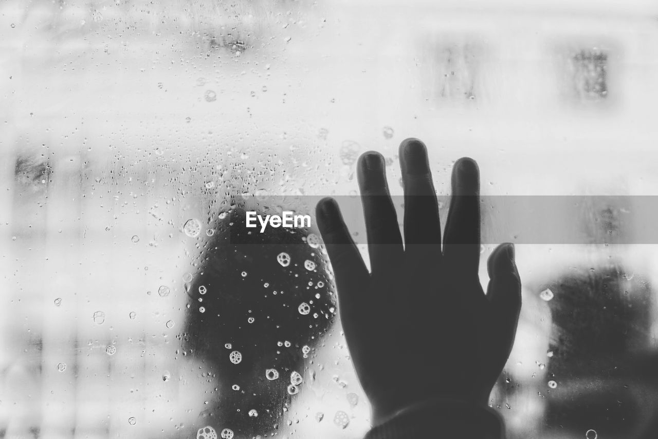 Cropped hand of person touching wet glass