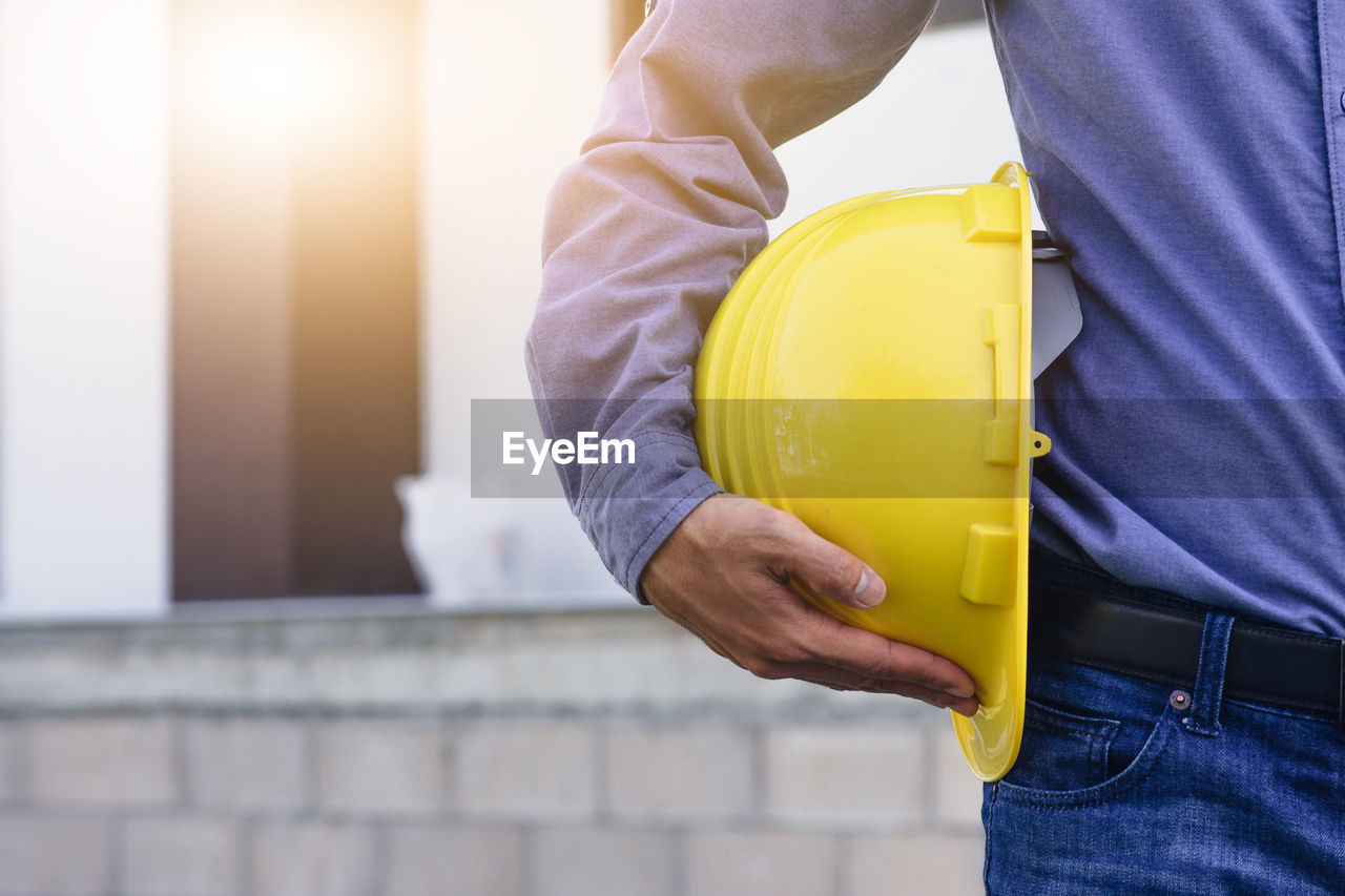 MIDSECTION OF MAN WORKING ON CONSTRUCTION