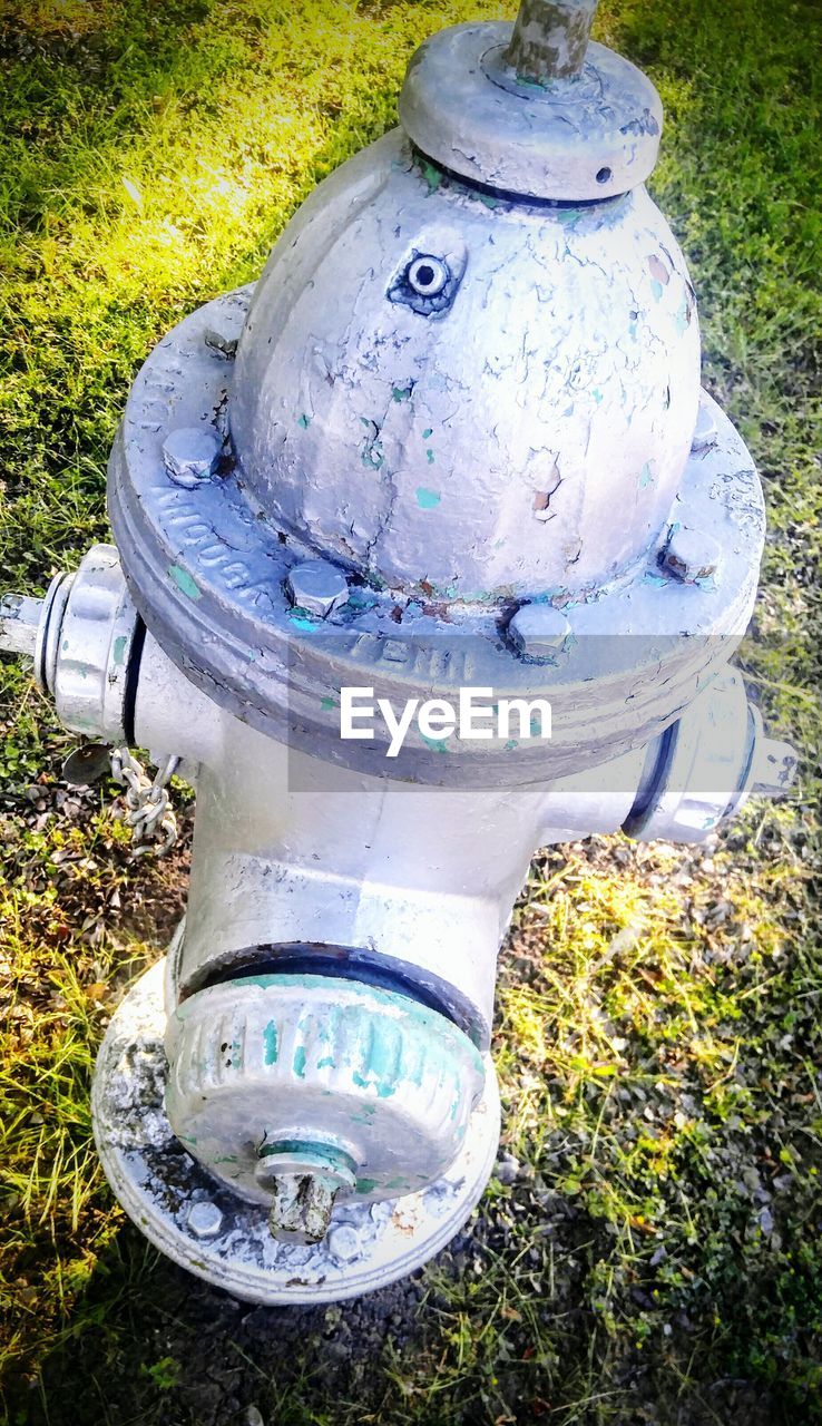 CLOSE-UP OF FIRE HYDRANT ON FIELD AGAINST BLUE WATER